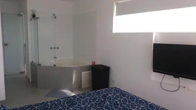 a bedroom with a tub and a bed and a television at Condominio Nuevo Paracas in Paracas