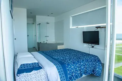 a bedroom with a bed and a tv and a tub at Condominio Nuevo Paracas in Paracas