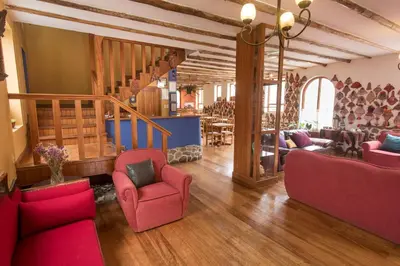 a living room with red chairs and a staircase at SAUCE Hotel Boutique in Ollantaytambo