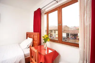 a room with a table and a bed and a window at Hostal Danna Inn in Cusco