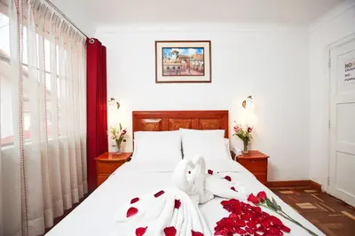 a bedroom with a bed with red roses and towels at Hostal Danna Inn in Cusco