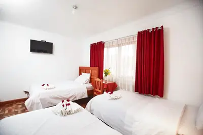 a room with three beds and red curtains at Hostal Danna Inn in Cusco