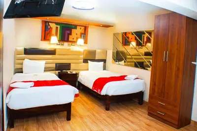 a room with two beds and a cabinet in it at Hotel Royal Qosqo in Cusco