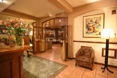 a lobby with a vase of flowers and a chair at Hotel Prisma Cusco in Cusco