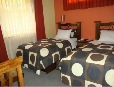 two beds in a room with orange walls at Ccapac Inka Ollanta Casa Museo in Ollantaytambo