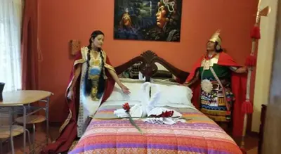 two women dressed in costumes standing around a bed at Ccapac Inka Ollanta Casa Museo in Ollantaytambo