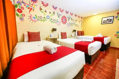 a room with two beds with red and white sheets at Mayu Boutique Hotel in Cusco