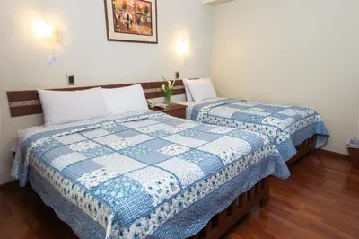 a bedroom with two beds with blue and white sheets at Antawasi Hotel in Cusco