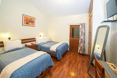 a hotel room with two beds and a flat screen tv at Antawasi Hotel in Cusco