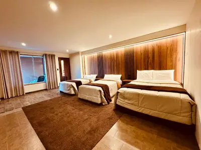 a hotel room with three beds and a window at Hotel Campo & Leña in Cieneguilla