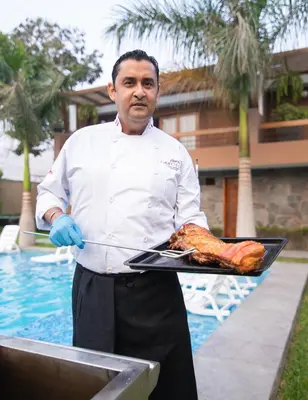a man holding a tray of meat on a grill at Hotel Campo & Leña in Cieneguilla