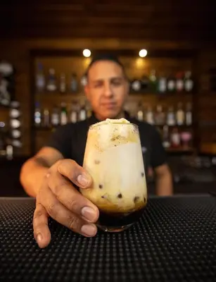 a man is holding a drink in a bar at Hotel Campo & Leña in Cieneguilla
