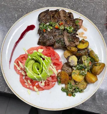 a plate of food with meat potatoes and vegetables at Hotel Campo & Leña in Cieneguilla