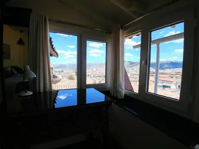 a room with two windows and a view of the city at Hostal Corihuasi in Cusco