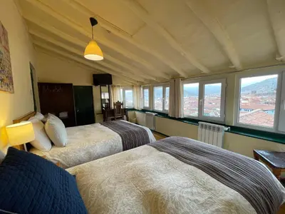 a hotel room with two beds and windows at Hostal Corihuasi in Cusco