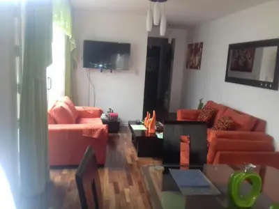 a living room with orange couches and a tv at Mi casa es su casa in Lima