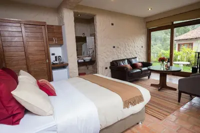 a bedroom with a large bed and a living room at Intiterra Apart Hotel Villas in Urubamba