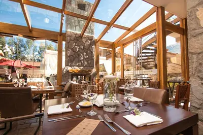 a dining room with a table and chairs and windows at Intiterra Apart Hotel Villas in Urubamba