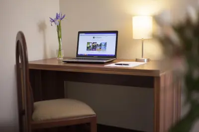 a laptop computer sitting on a wooden desk with a lamp at El Angolo in Lima