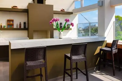 a kitchen with three bar stools and a counter with purple flowers at El Angolo in Lima
