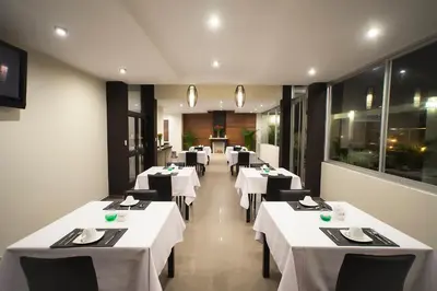 a dining room with white tables and black chairs at El Angolo in Lima