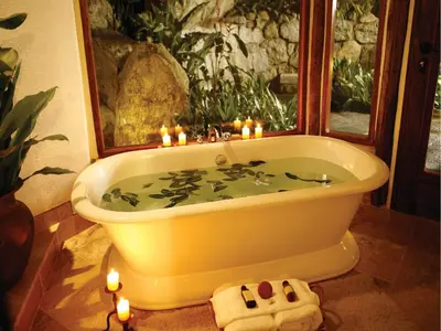 a bath tub with lit candles in a bathroom at Inkaterra Machu Picchu Pueblo Hotel in Machu Picchu
