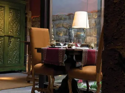 a table with two chairs and a lamp and wine glasses at Inkaterra La Casona Relais & Chateaux in Cusco