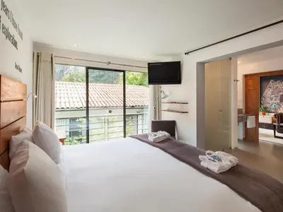 a bedroom with a large white bed and a large window at El MaPi by Inkaterra in Machu Picchu
