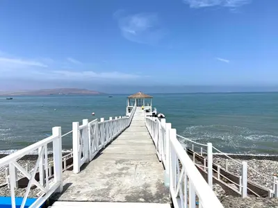 a wooden boardwalk leading into the ocean on a beach at Duplex 1 Fila Vista Bahía Paracas - Sotavento 501 T3 in Paracas