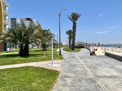 a sidewalk next to a beach with palm trees at Duplex 1 Fila Vista Bahía Paracas - Sotavento 501 T3 in Paracas