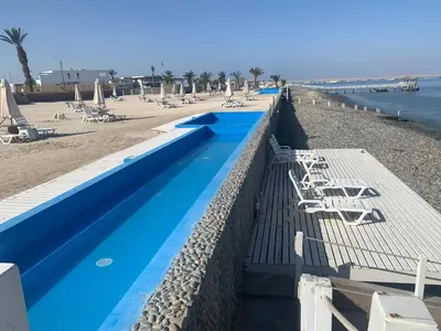 a swimming pool next to a beach with chairs at Duplex 1 Fila Vista Bahía Paracas - Sotavento 501 T3 in Paracas