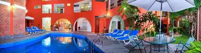 a swimming pool with chairs and a table and an umbrella at Hotel Princess in Ica