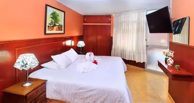 a bedroom with a bed with white sheets and a television at Hotel Princess in Ica