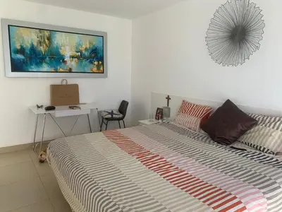a bedroom with a bed and a desk and a painting at Condominios Nauticos Nuevo Paracas in Paracas