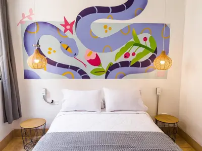 a bedroom with a bed and a painting on the wall at Supertramp Hostel Machupicchu in Machu Picchu