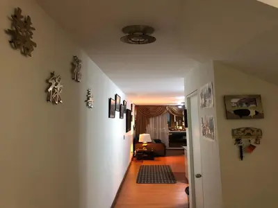 a hallway leading to a living room with art on the walls at A Perfect Vacation Getaway Apartment in Lima