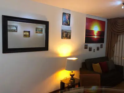 a living room with a couch and a table with a lamp at A Perfect Vacation Getaway Apartment in Lima