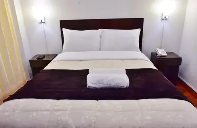 a bed in a room with two nightstands and a bed with two towels at Machupicchu Guest House in Machu Picchu