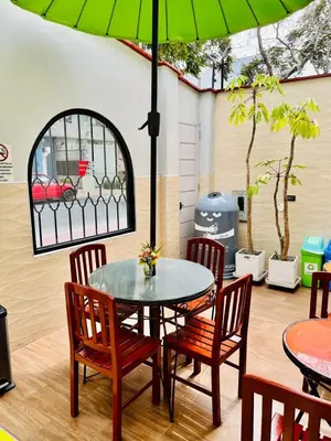 a table and chairs with a green umbrella at Imperial Inn Hospedaje Turistico in Lima
