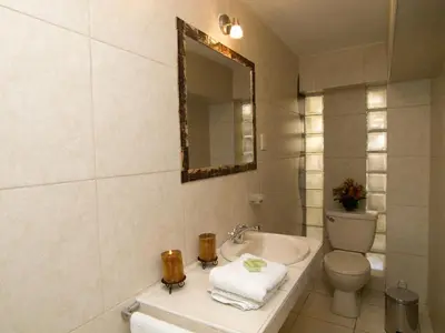 a bathroom with a sink and a toilet and a mirror at Hostal Samichay in Cusco