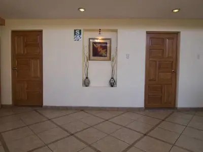 a room with two wooden doors and a white wall at Hostal Samichay in Cusco
