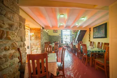 a dining room with tables and chairs and a stone wall at Siete Ventanas in Cusco