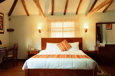 a bedroom with a bed and a desk and a window at Siete Ventanas in Cusco