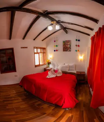 a bedroom with a red bed with a red blanket at Hostal Tu Hogar in Cusco