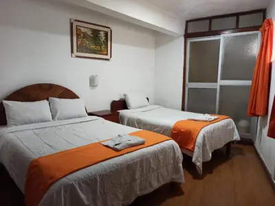 a hotel room with two beds and a window at Hostal Tu Hogar in Cusco