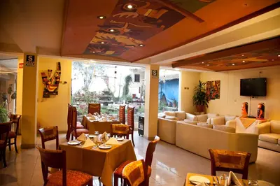 a restaurant with tables and chairs and a couch at Taypikala Hotel Cusco in Cusco