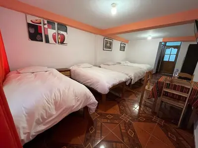 a group of four beds in a room at Hostal Apu Qhawarina in Ollantaytambo