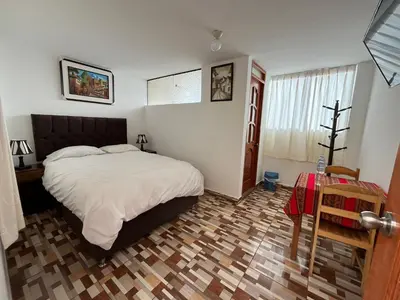 a bedroom with a large bed and a wooden floor at Hostal Apu Qhawarina in Ollantaytambo