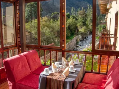 a balcony with a table and chairs and a view of a river at Sol Ollantay Boutique Hotel in Ollantaytambo