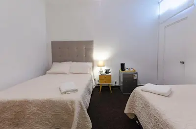 a bedroom with two beds and a table with a lamp at Jose Luis Hostal Boutique in Lima